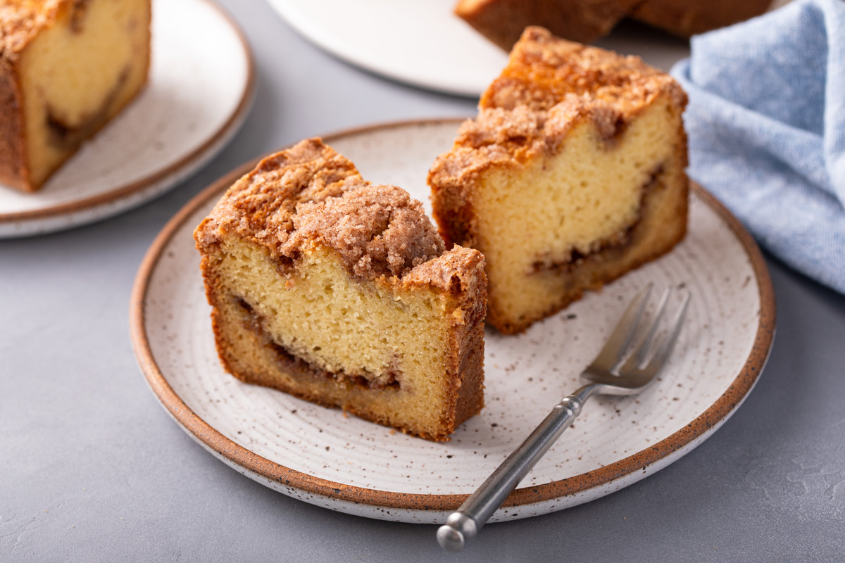 Two slices of sour cream coffee cake on a plate next to a fork.