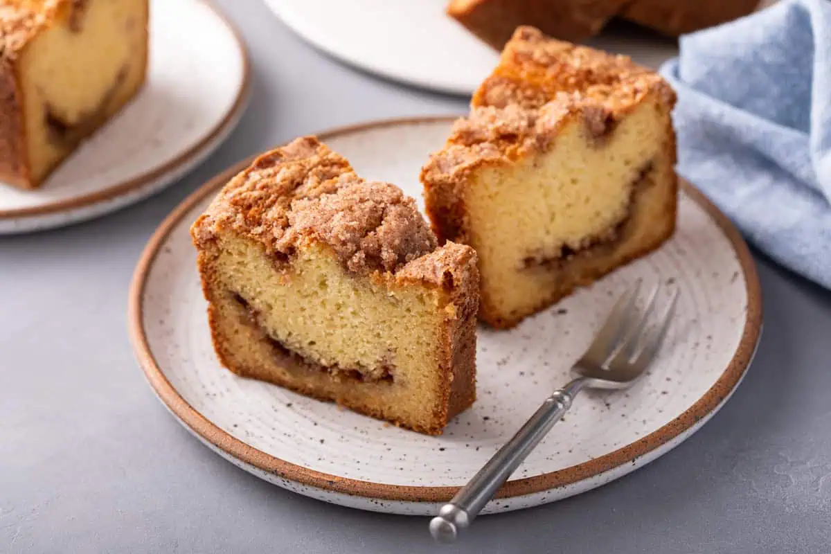 Two slices of sour cream coffee cake on a plate next to a fork.