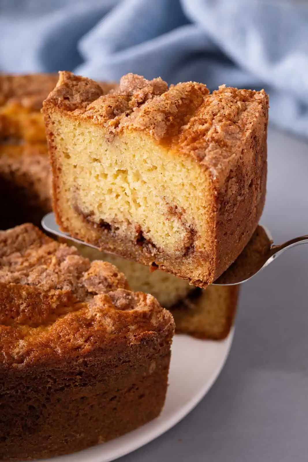 Cake server lifting up a slice of sour cream coffee cake.