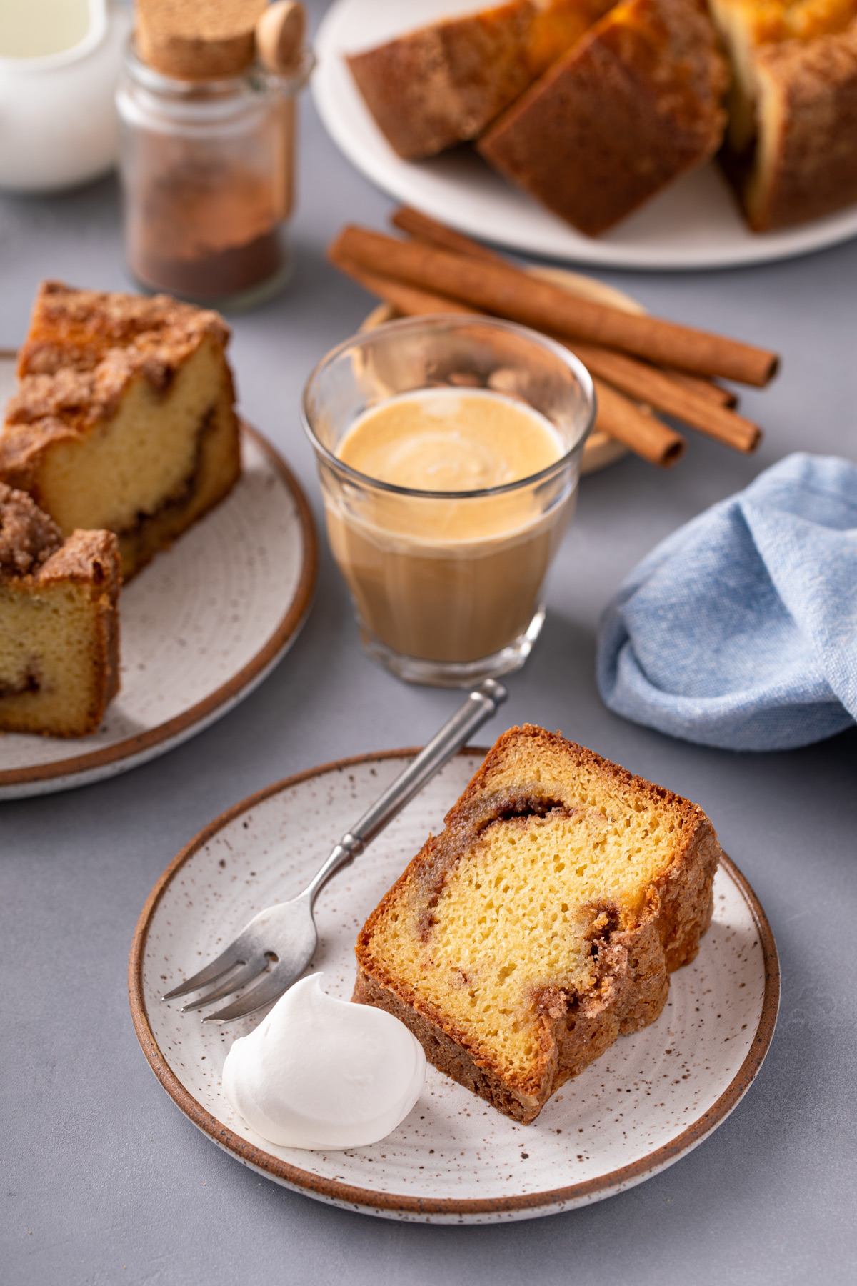 Two plates holding sour cream coffee cake next to a glass of espresso.