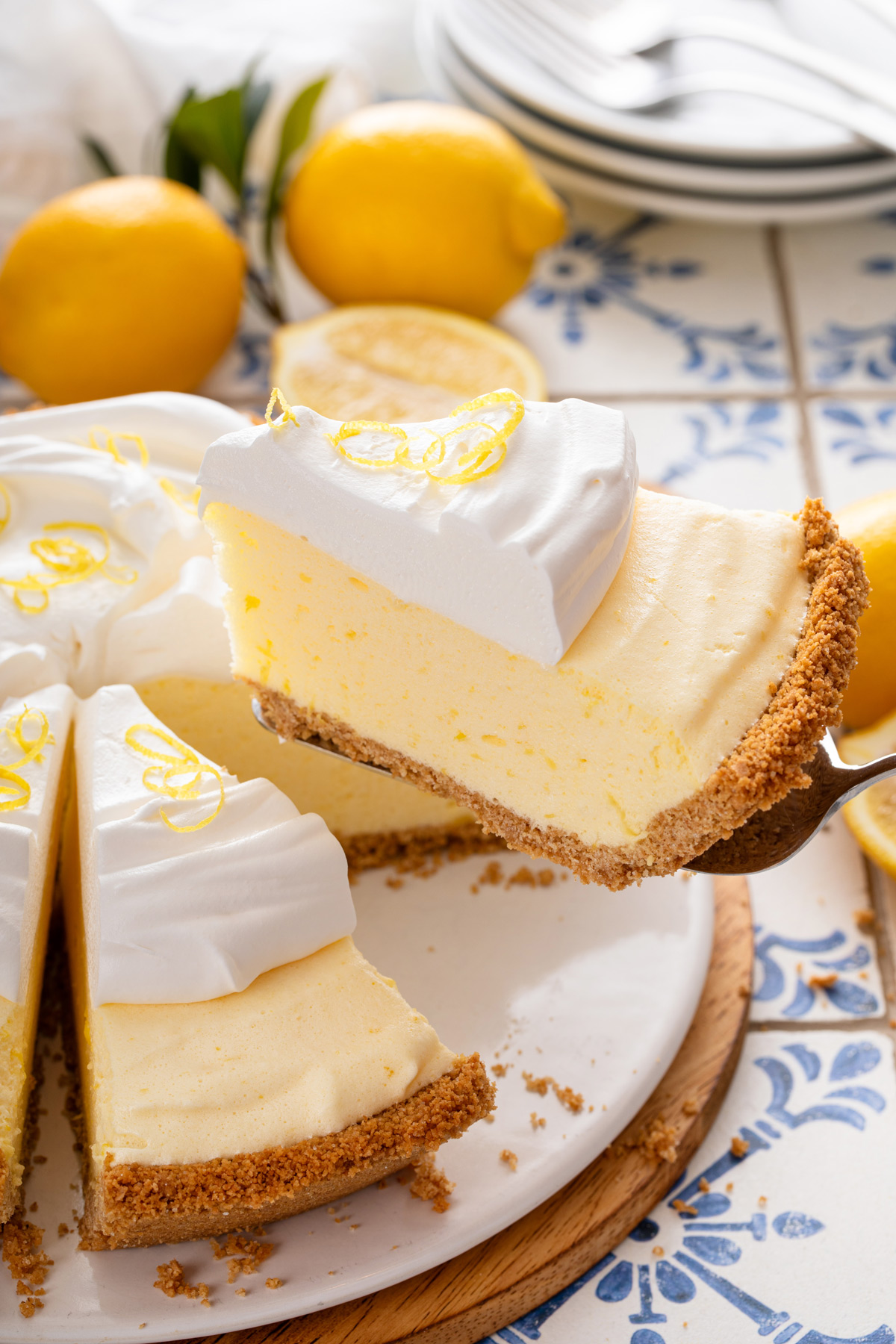 Pie server lifting up a slice of lemon chiffon pie topped with whipped cream.