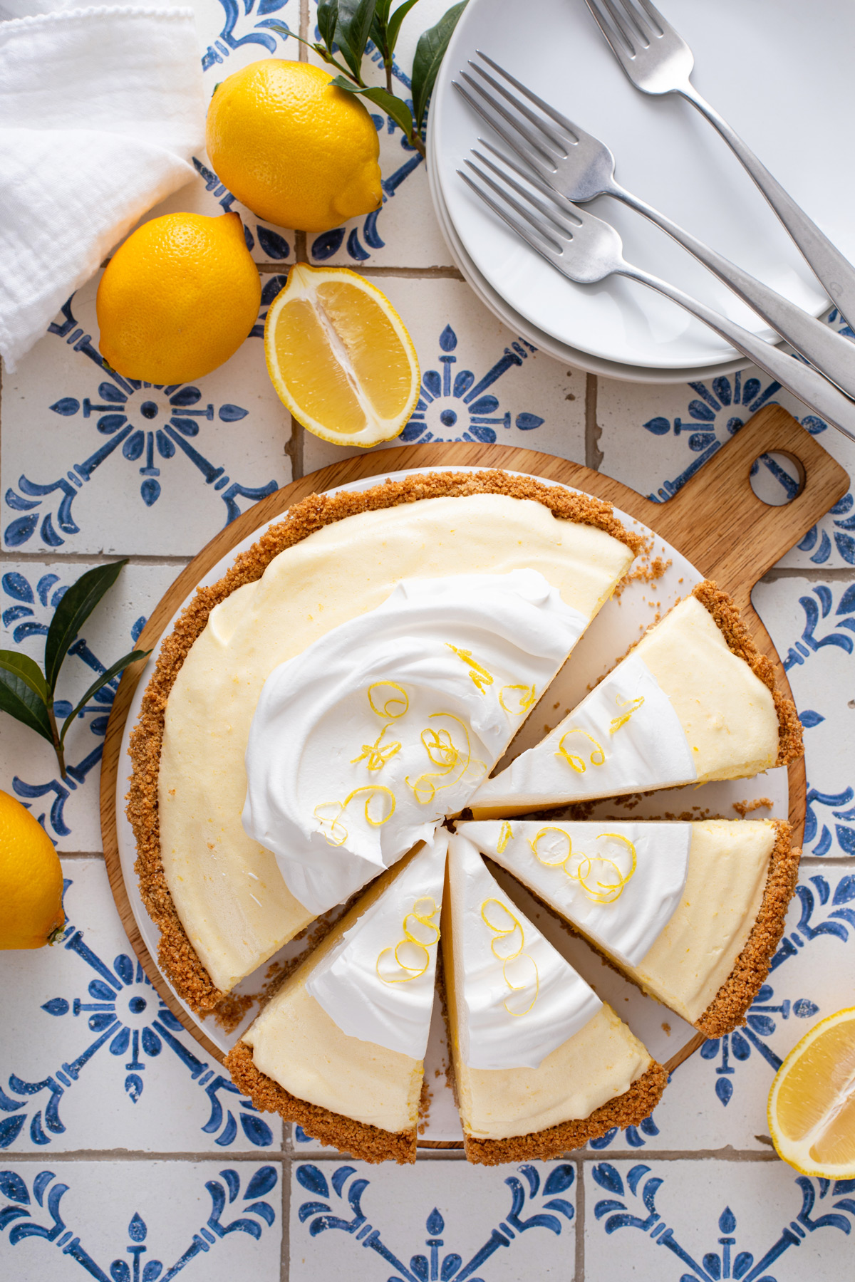 Overhead view of a sliced lemon chiffon pie topped with whipped cream and lemon zest.